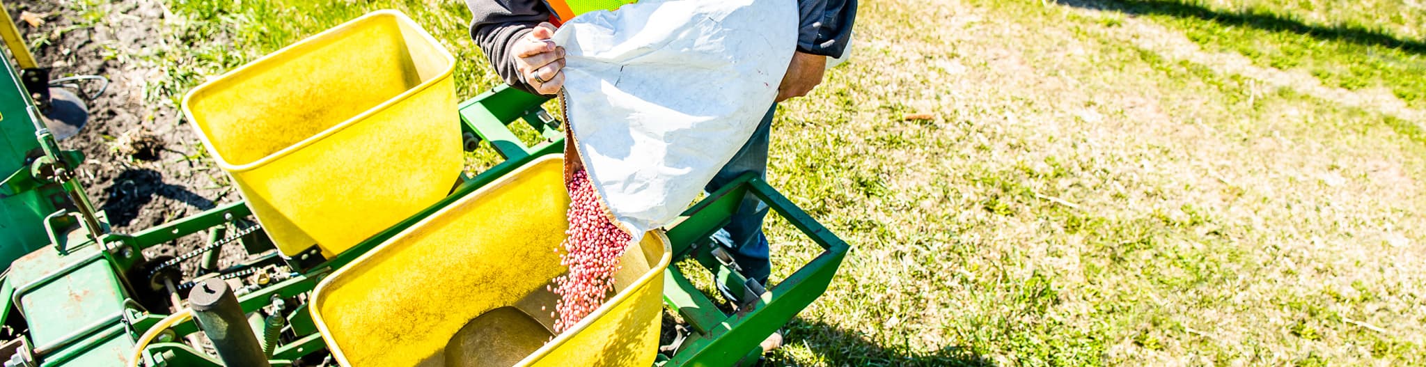 Man pouring seeds into a planter tractor attachment